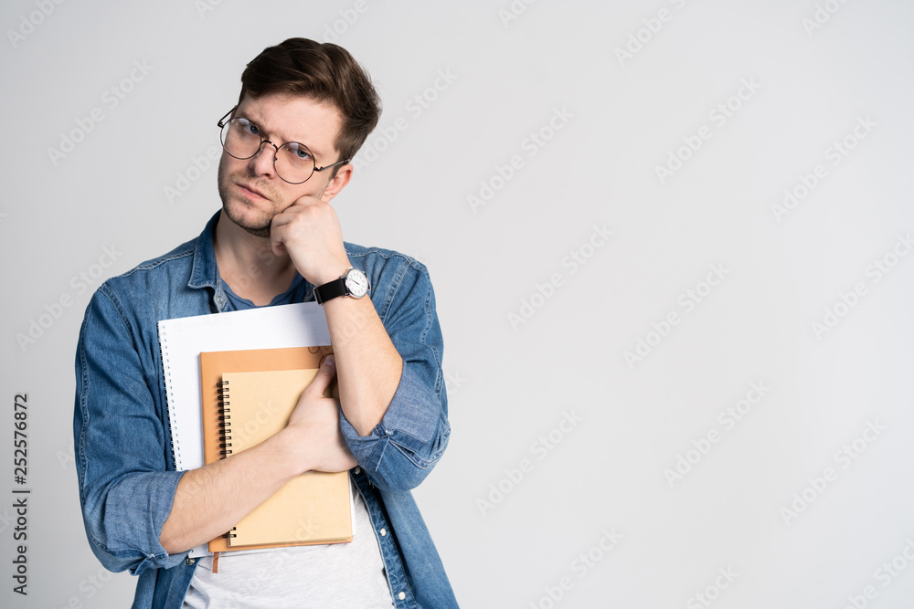 Confident student. Studio portrait of handsome young man holding books. Isolated on white.