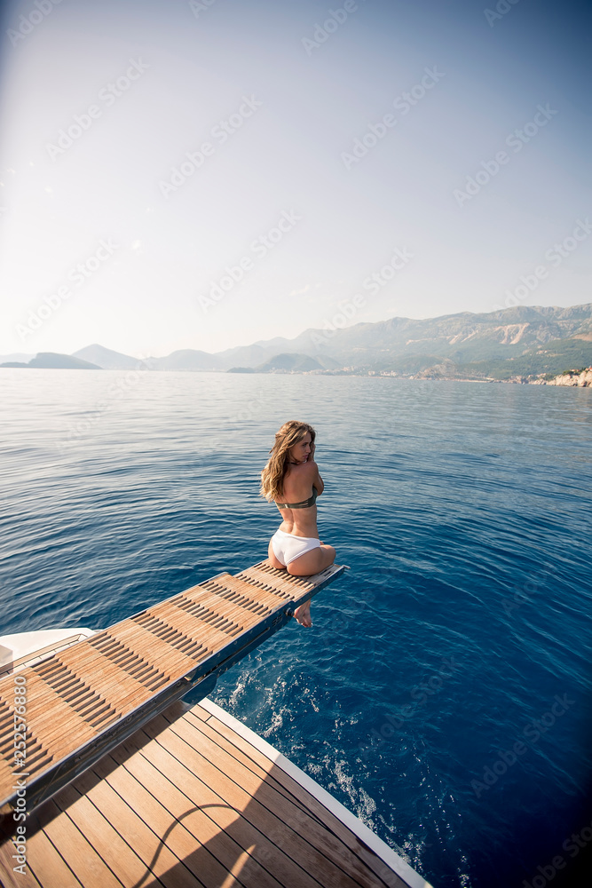 Pretty young woman relaxing on the yacht on sea at sunny day