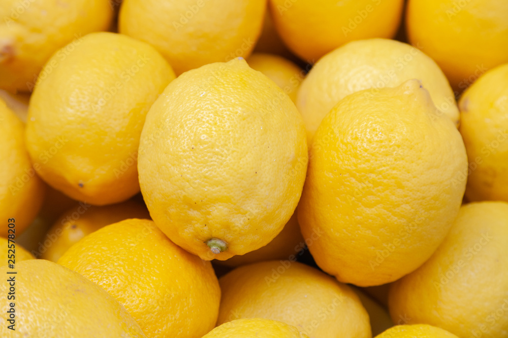 Closeup pile of fresh yellow lemons on counter at the farmers market. New Year fruit concept, fresh squeezed vitamin juice, healthy foods Closeup pile of fresh yellow lemons on counter at the farmers market. New Year fruit concept, fresh squeezed vitamin juice, healthy foods