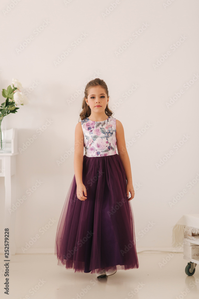 Happy child female in purple dress. Beautiful makeup and hairstyle Happy child female in purple dress. Beautiful makeup and hairstyle