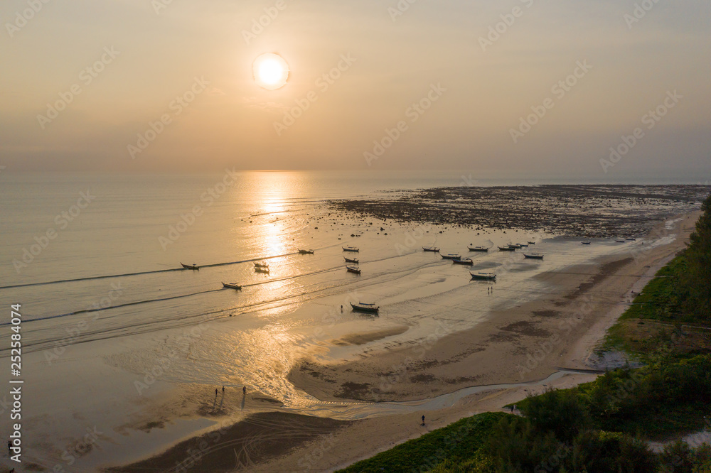 Obraz premium Aerial drone view of a tropical sunset over the ocean with traditional longtail boats at anchor (Pakarang Cape, Phang Nga, Thailand)