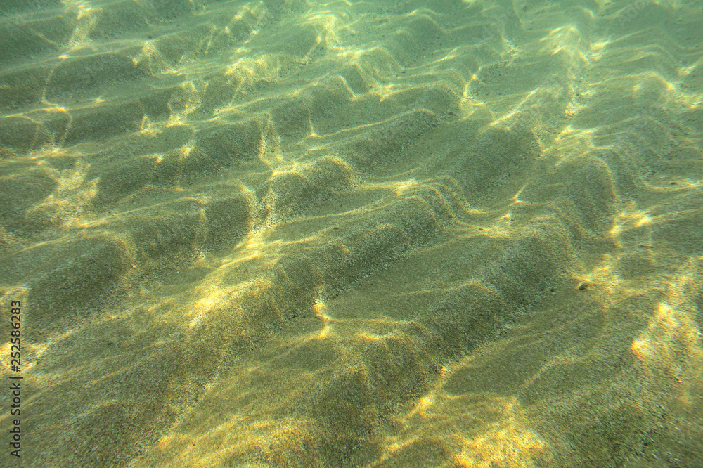 Underwater photo - sun shines on sand "dunes" on sea floor in shallow water near beach, abstract marine background. - obrazy, fototapety, plakaty 