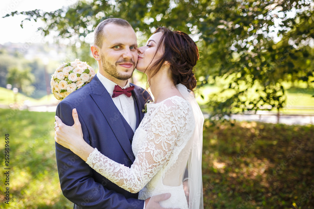 The bride and groom walks in park in summer sunny day. Walk the newlyweds. Wedding day. The best day of a young couple The bride and groom walks in park in summer sunny day. Walk the newlyweds. Wedding day. The best day of a young couple