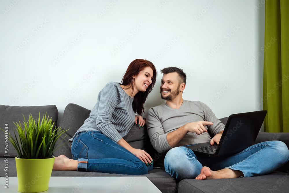 The girl and the guy have fun in two for the laptop. The concept of family relationships, watching movies together, sharing time. The girl and the guy have fun in two for the laptop. The concept of family relationships, watching movies together, sharing time.