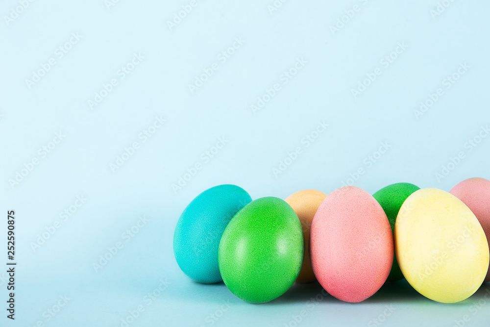 Bunch of blank painted Easter eggs of different pastel color isolated on bright baby blue background with a lot of copy space for text. Front view, flat lay, close up. Bunch of blank painted Easter eggs of different pastel color isolated on bright baby blue background with a lot of copy space for text. Front view, flat lay, close up.