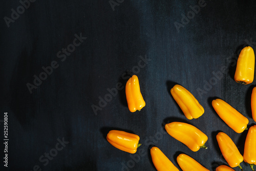 yellow pepper over dark concrete background with space for text. Top view of fresh organic vegetables on a black stone table. Minimalist style. Flat lay. The view from the top. Copy space.