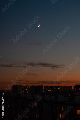 Moon rising over sleeping district's houses