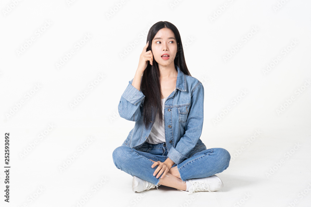Thinking asian woman sitting on floor isolated on white background.Asian female model smiling looking up.woman pointing fingers away while sitting on a floor with legs crossed isolated Thinking asian woman sitting on floor isolated on white background.Asian female model smiling looking up.woman pointing fingers away while sitting on a floor with legs crossed isolated