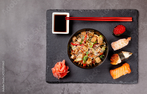 The concept of Japanese cuisine. Japanese lunch of noodles, sushi with shrimp, red caviar, eel, tuna. Soy sauce and red chinese sticks. background image. Top view, copy space