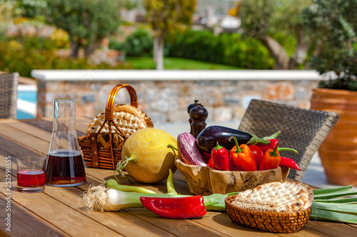 Fruits, vegetables, wine and bread on the table in the summer garden, Crete, Greece