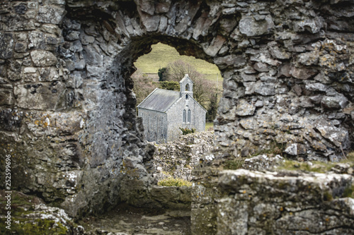 A small church seen through the Hole in the Wall (most likely a window in its time) at the ruins of Rock of Dunamase, in county Laois, Ireland   photo