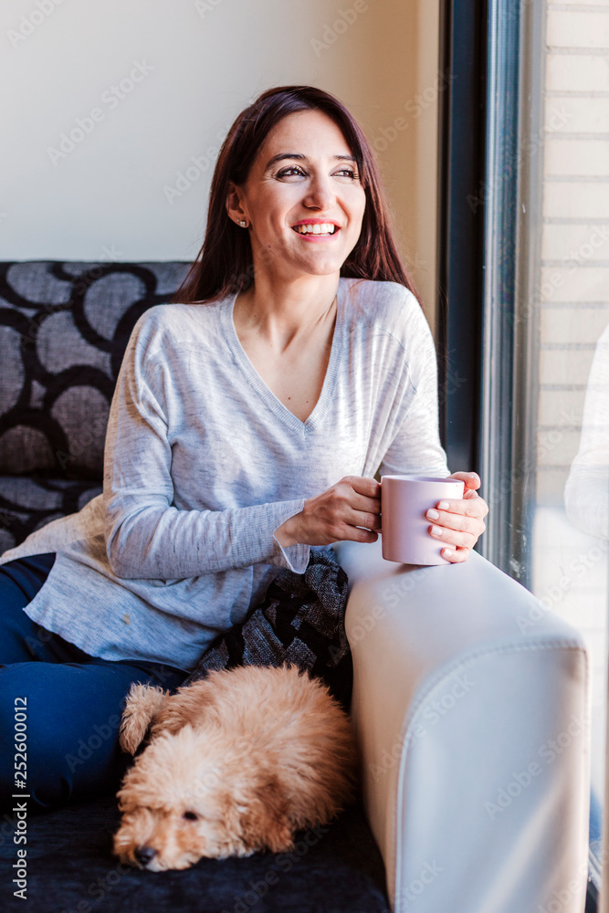 portrait of a Cute brown toy poodle with his young woman owner at home, daytime, indoors. portrait of a Cute brown toy poodle with his young woman owner at home, daytime, indoors.