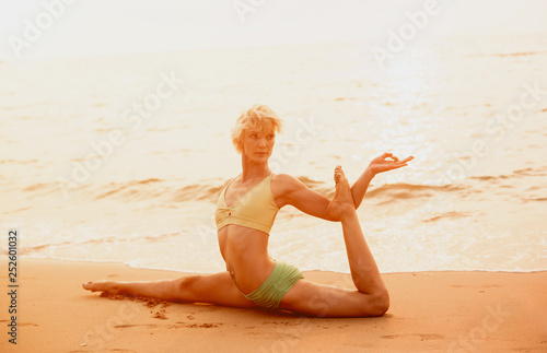 Beautiful young woman practic yoga at the beach. Early morning exercise photo