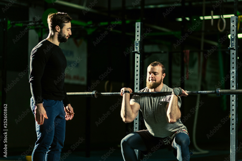 Naklejka premium Man with heavyweight barbell in the dark gym.