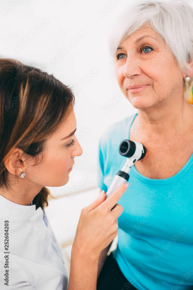 Doctor examining patient skin moles with dermoscope Doctor examining patient skin moles with dermoscope