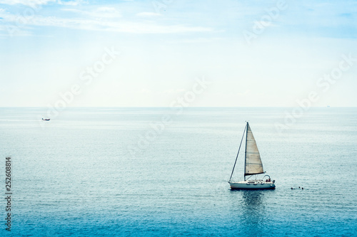 Sail boat in sea near Acitrezza rocks of the Cyclops, Catania, Sicily, Italy.