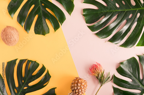 Tropical summer flat lay on yellow background with palm leaf, coconut, pineap...