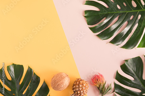 Tropical summer flat lay on yellow background with palm leaf, coconut, pineap...
