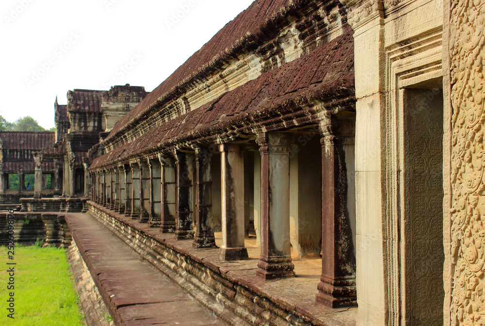 Exterior a open stone gallery or corridor of Angkor Wat temple at Siem Reap, Cambodia. Largest religious monument in the world and popular tourist attraction. Object a UNESCO World Heritage Site.