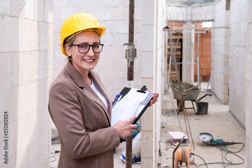 Photos Frau als Architektin, Ingenieurin mit Helm, Bauplan, Plänen auf einer Baustelle