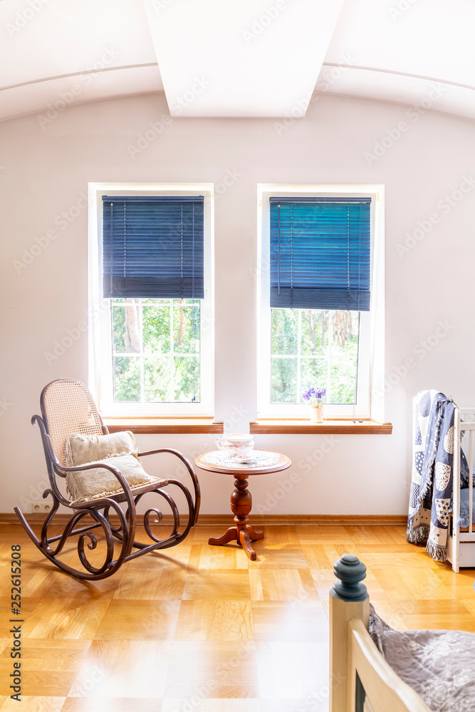 Wooden rocking chair next to table in living room interior with blue blinds at windows. Real photo Stock Photo Adobe Stock