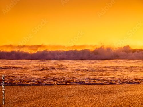 Waves splashing on a beach during sunset