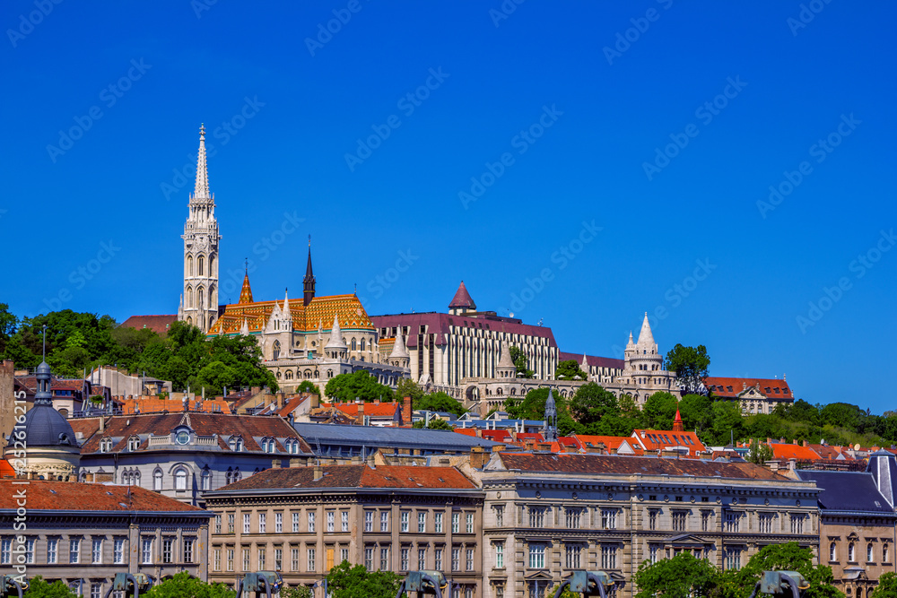 View of beautiful historic Budapest architecture with colorful buildings, Fisherman`s Bastion, Matthias church, green trees and blue sky. 