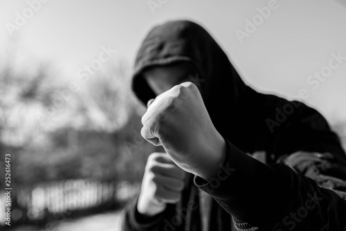 Foto Unidentifiable teenage boy attacking with hes bare hands, focus on the fist in black and white, conceptual image of juvenile delinquency