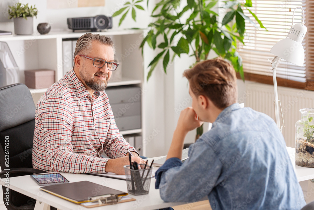 Senior account manager and young man during job interview in small firm Senior account manager and young man during job interview in small firm