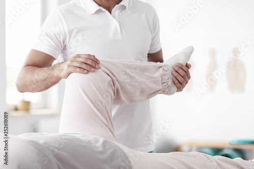 Physiotherapist holding a leg of his patient
