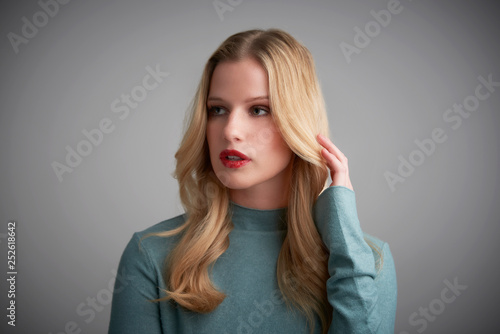 Studio portrait of beautiful young woman posing at grey background
