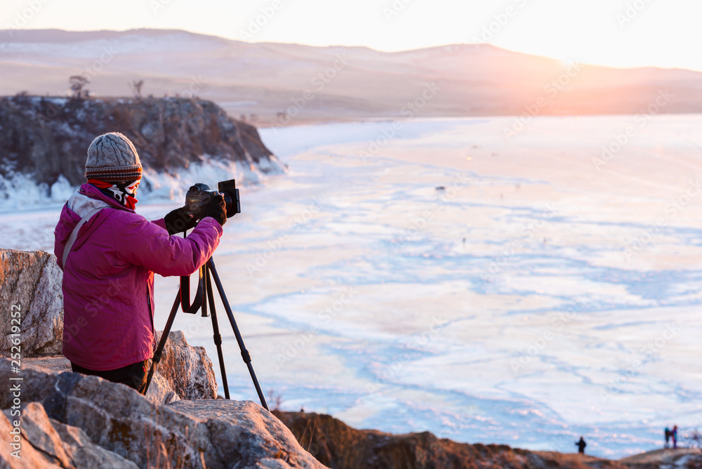 Photographer or Traveller using a professional DSLR camera take photo beautiful landscape of Baikal lake at sunset winter. The most tourist attraction in Rusia - Recreation and outdoor travel concept.