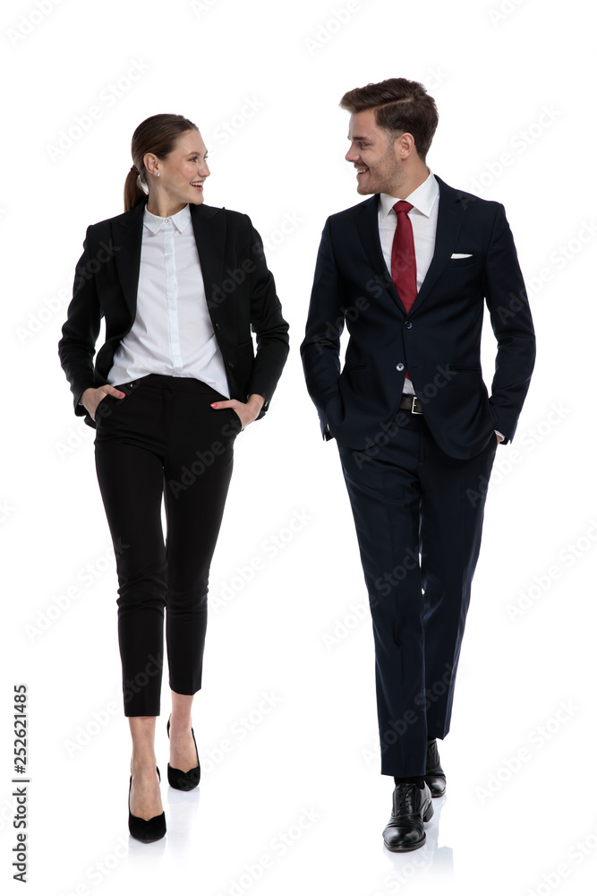 couple in business suits walking,talking with hands in pockets couple in business suits walking,talking with hands in pockets