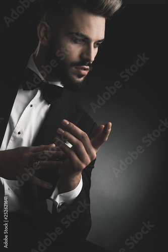 man in tuxedo with hands together looking away