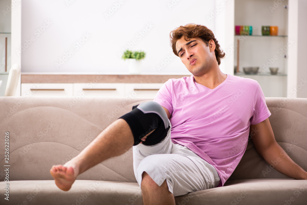 Young man with injured knee recovering at home Young man with injured knee recovering at home
