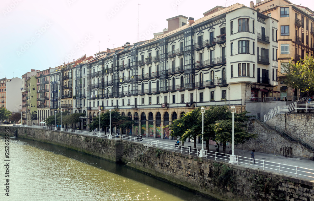 Bilbao, Spain-September 2018. River of the city with people in the shore. Describe the city life.