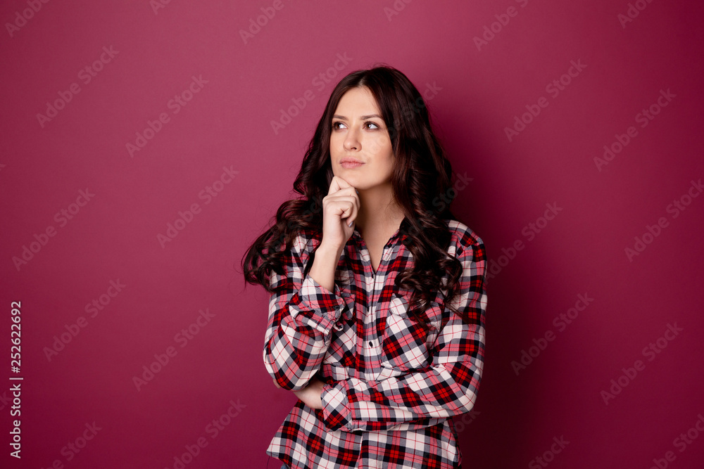 Closeup photo of thinking attractive woman posing isolated over the dark pink backgrownd