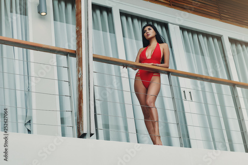 Asian young woman in red swimsuit standing on terrace