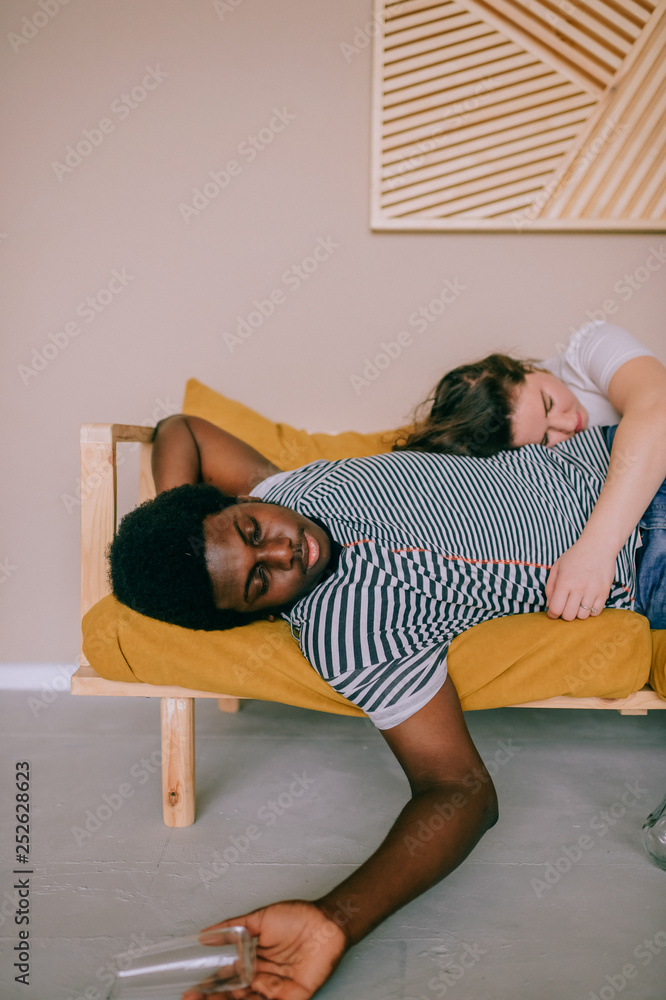 Funny blurred soft focus portrait of odd interracial drunk couple sleeping  on bed at home after