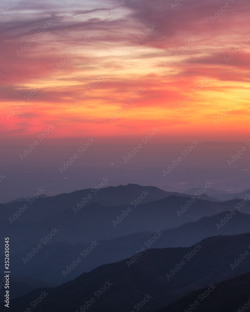 A beautiful orange and pink sky over layered silhouetted mountains during sunset. Kings Canyon National Park. 