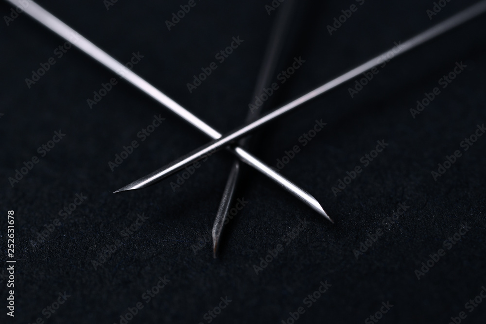 Old rare metallic medical needles isolated on gray background. Needles new and clean. Top view. Sharp needle tips and defocused background. Old rare metallic medical needles isolated on gray background. Needles new and clean. Top view. Sharp needle tips and defocused background.