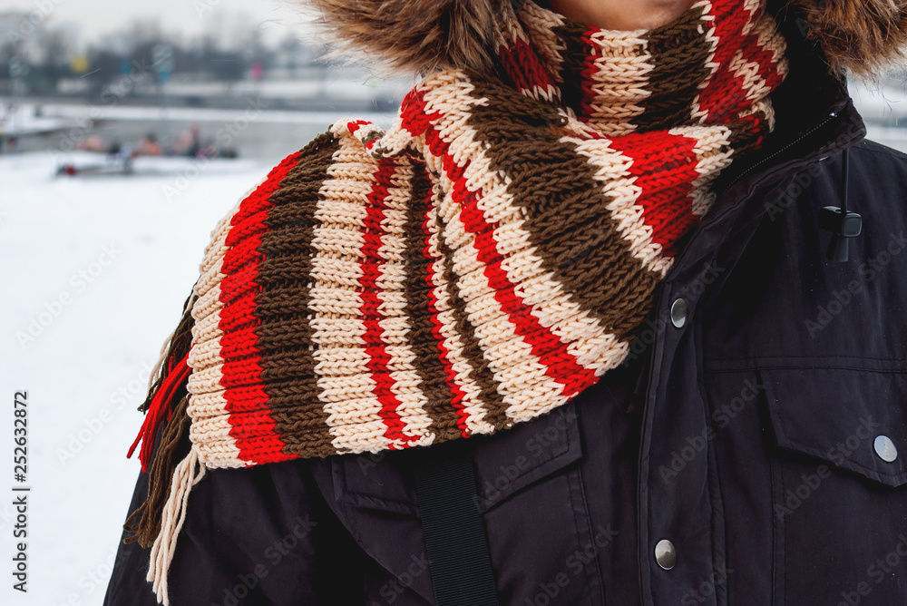 Man in hand knitted scarf with colorful stripes. Clothing for cold winter day.