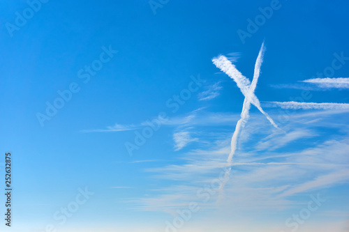 White clouds as an x shape sign against a saturated blue sky with copy space on the left    photo