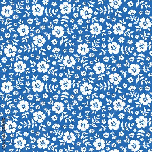 Seamless ditsy floral pattern in vector. Small white flowers on a blue background.	