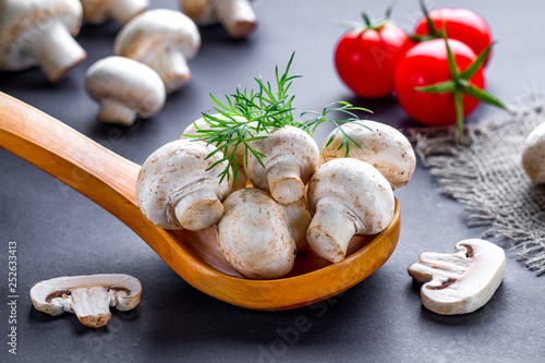 White mushrooms in wooden spoon with dill. Cooking homemade dishes of tomatoes cherry and fresh ripe champignon