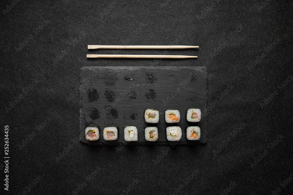 Sushi rolls, maki, nigiri on black stone slate on dark background copy space Sushi rolls, maki, nigiri on black stone slate on dark background copy space