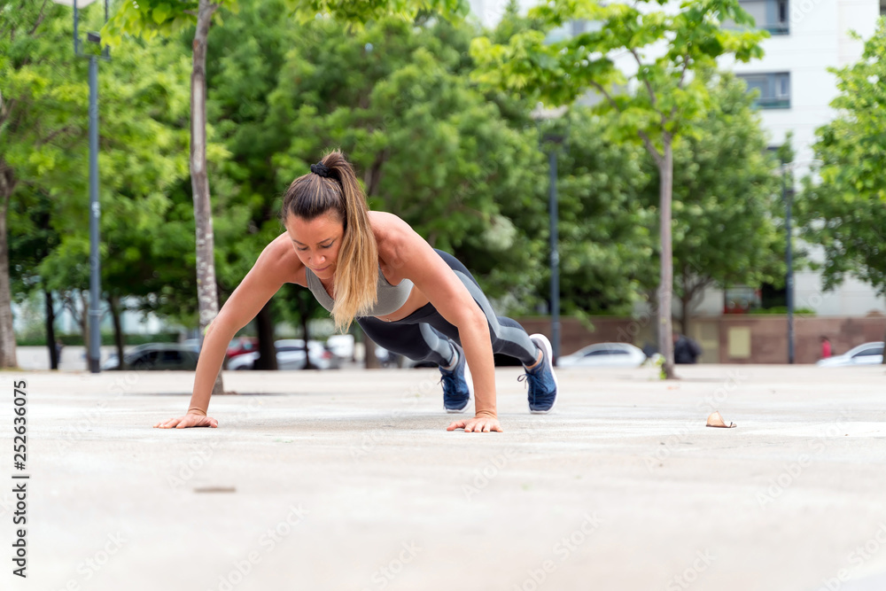 An athletic woman doing push ups in the park An athletic woman doing push ups in the park
