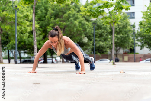 An athletic woman doing push ups in the park
