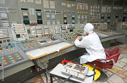 Photography Operator sits in front of the main control board in a control operations room of