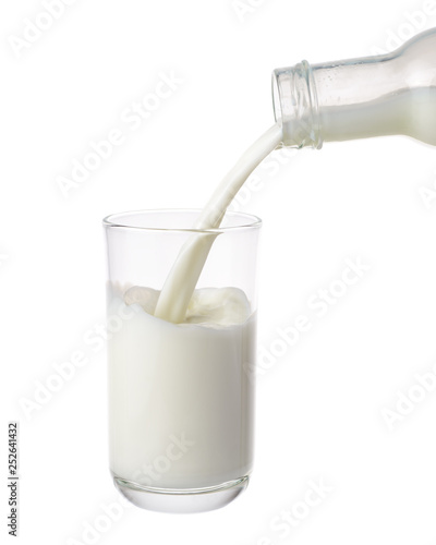 Pouring milk from bottle into glass isolated on white background.